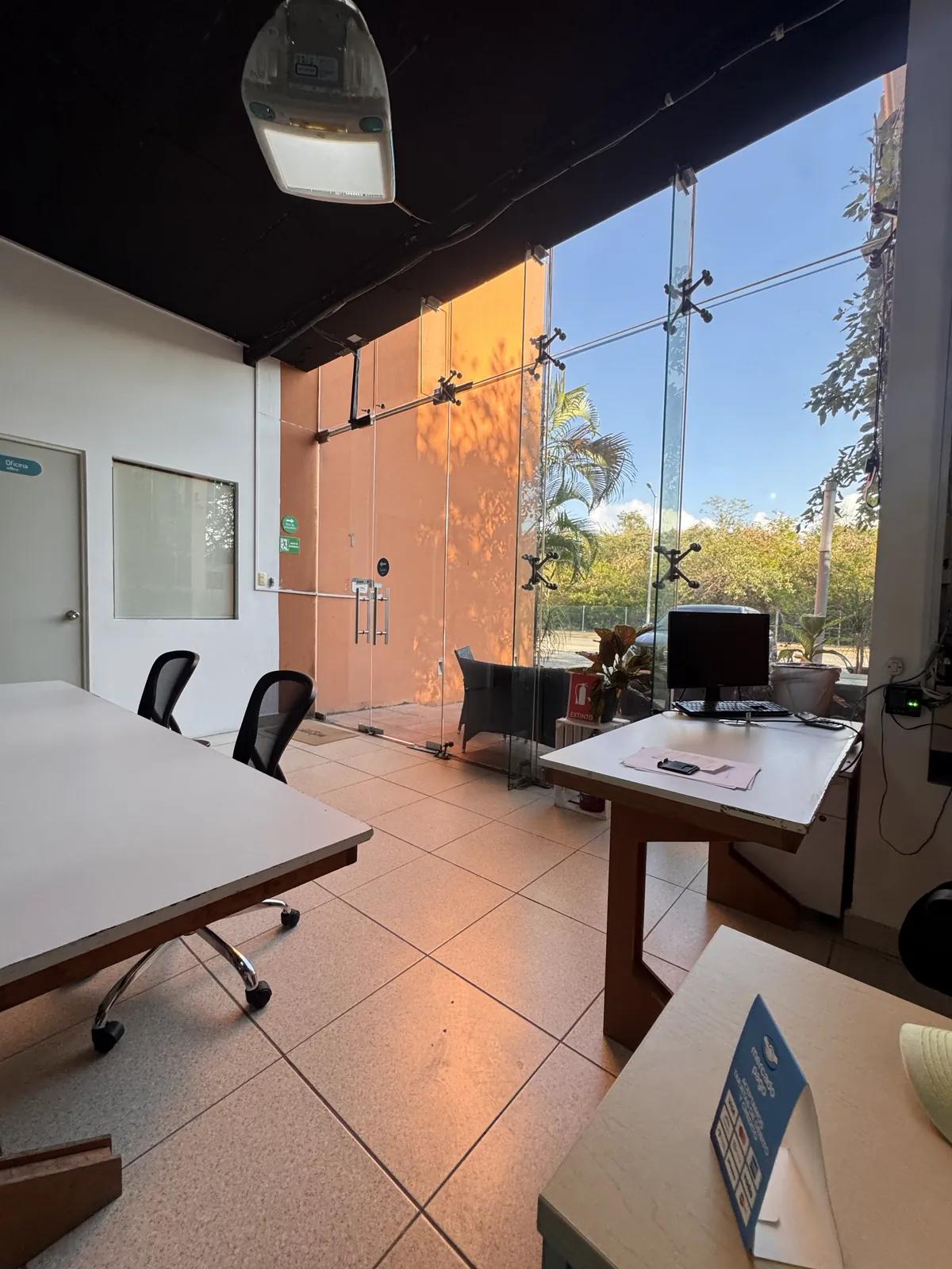 Entrada de Kiin Hub Cowork con puerta de cristal, recepción y mesa de trabajo, Playacar Fase II