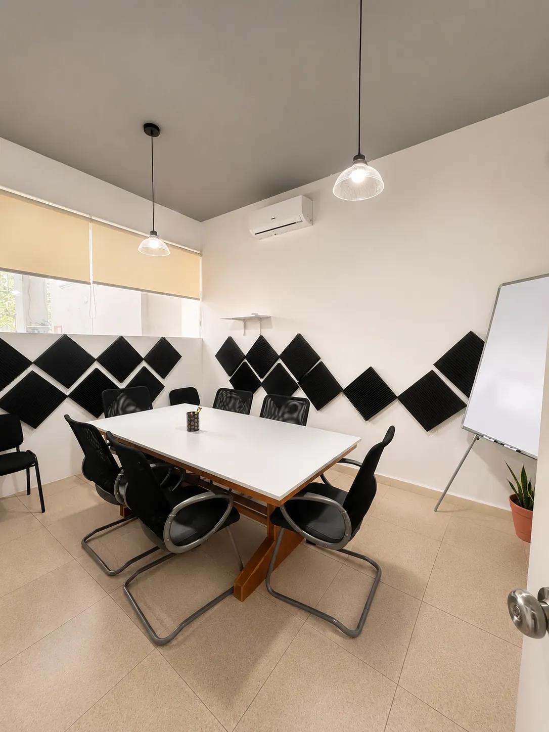 Sala de juntas de Kiin Hub Cowork con mesa para ocho personas, pizarrón y paneles acústicos